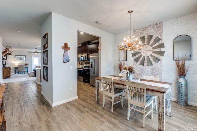 dining area with light wood-style floors, baseboards, visible vents, and ceiling fan with notable chandelier