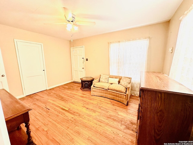 living room with ceiling fan, light wood-style flooring, and baseboards