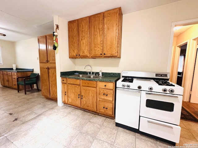 kitchen with range with two ovens, dark countertops, brown cabinetry, and a sink