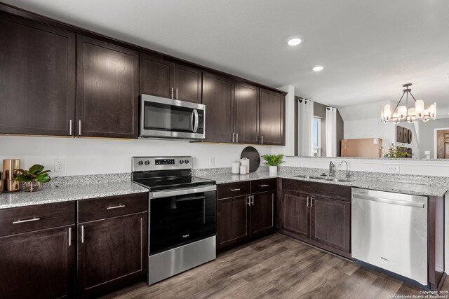 kitchen with dark brown cabinetry, dark wood-style floors, appliances with stainless steel finishes, light stone countertops, and a sink