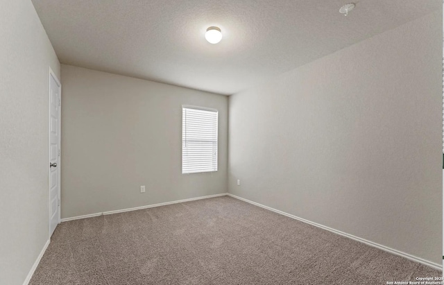 spare room with carpet flooring, a textured ceiling, and baseboards