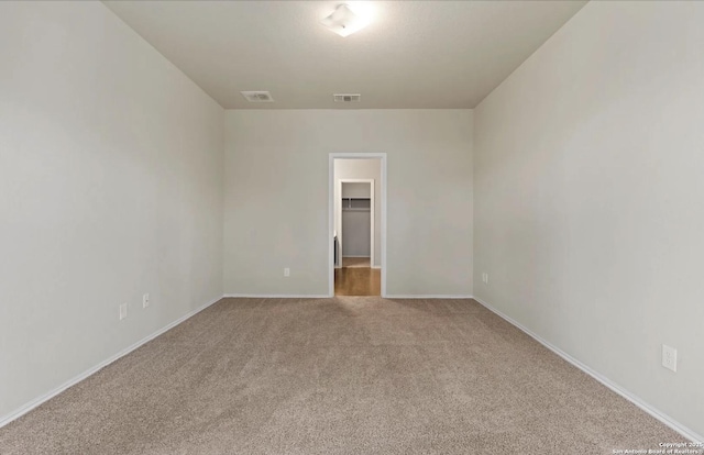 empty room with light carpet, visible vents, and baseboards