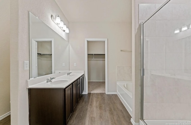 bathroom featuring a bath, a stall shower, a sink, and wood finished floors