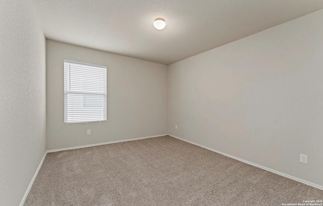 carpeted spare room featuring baseboards