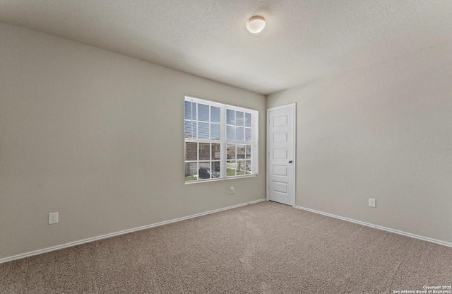 carpeted spare room with baseboards and a textured ceiling