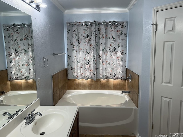 bathroom with a textured wall, ornamental molding, a garden tub, and vanity