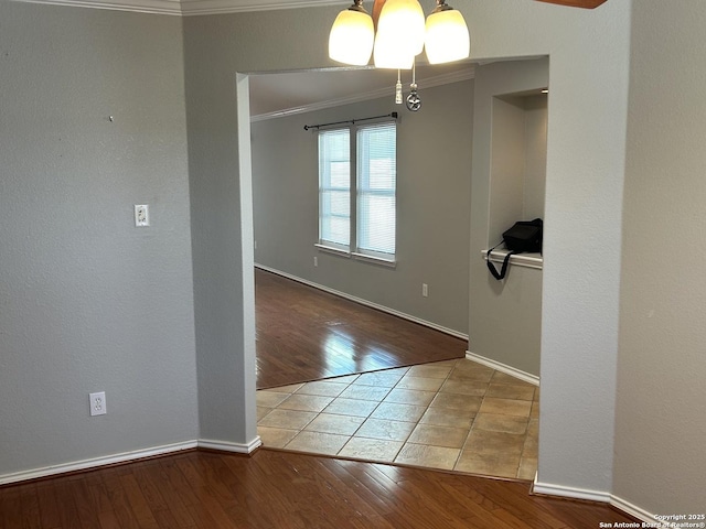 unfurnished dining area with baseboards, ornamental molding, a chandelier, and wood finished floors