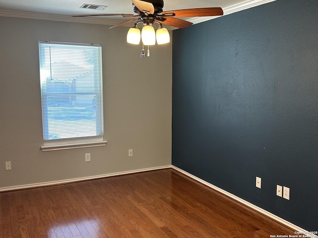 empty room with visible vents, baseboards, a ceiling fan, wood finished floors, and crown molding