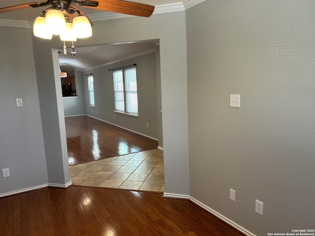 spare room featuring baseboards, hardwood / wood-style floors, a ceiling fan, and crown molding