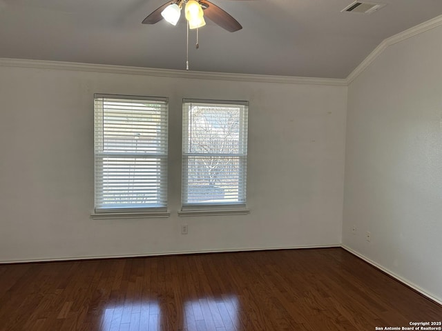 empty room featuring wood finished floors, a ceiling fan, visible vents, vaulted ceiling, and crown molding