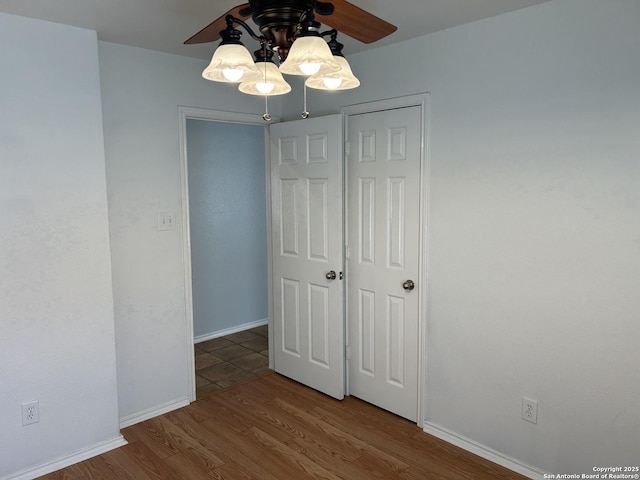 unfurnished bedroom featuring a ceiling fan, baseboards, and wood finished floors