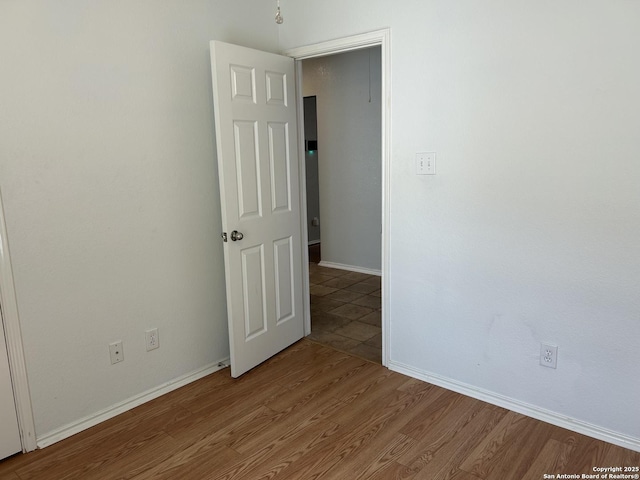 spare room featuring baseboards and wood finished floors