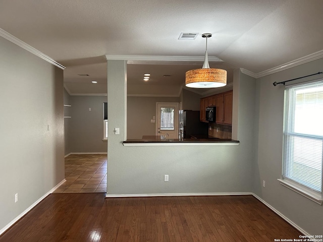 kitchen featuring visible vents, freestanding refrigerator, hardwood / wood-style floors, dark countertops, and crown molding