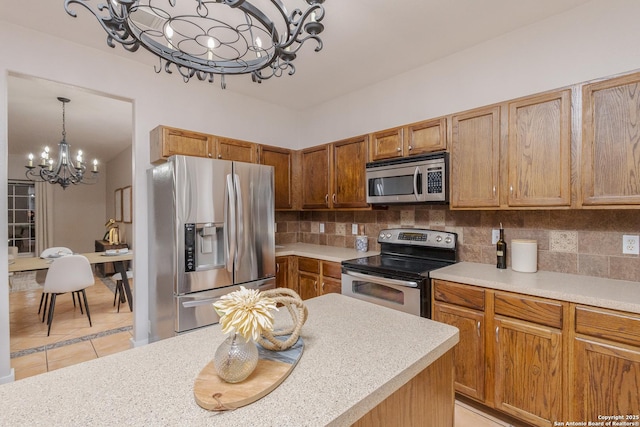 kitchen with light tile patterned flooring, light countertops, appliances with stainless steel finishes, decorative backsplash, and an inviting chandelier