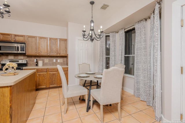 dining room featuring light tile patterned floors, visible vents, and an inviting chandelier