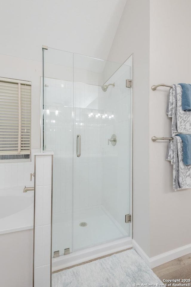 full bathroom featuring a garden tub, a stall shower, wood finished floors, and baseboards