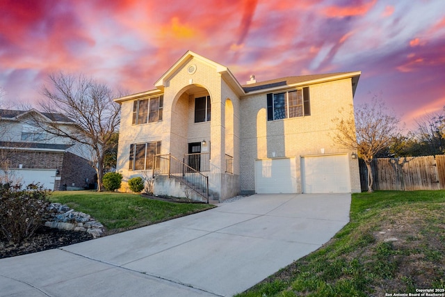 view of front of home with an attached garage, brick siding, fence, concrete driveway, and a front yard