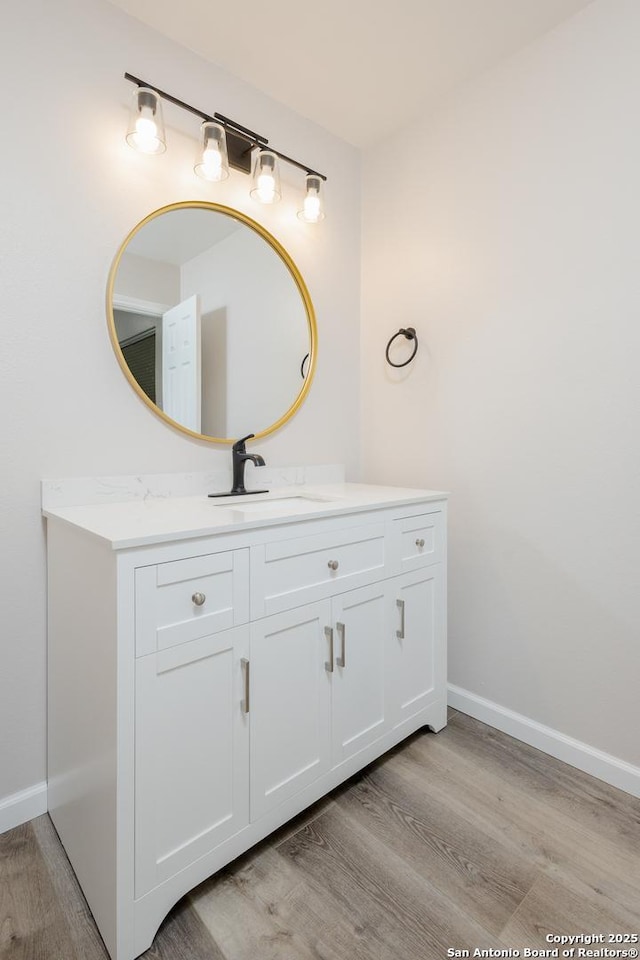 bathroom featuring wood finished floors, vanity, and baseboards