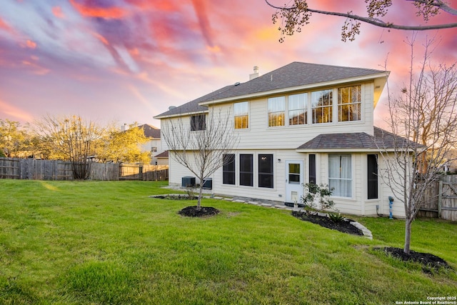 rear view of house with central air condition unit, a lawn, a chimney, and fence