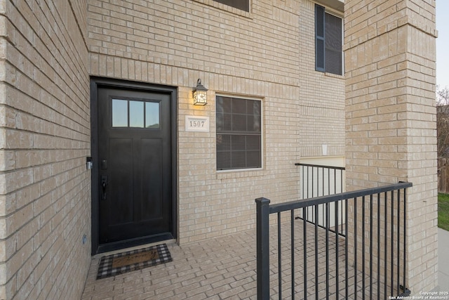 property entrance featuring brick siding and fence