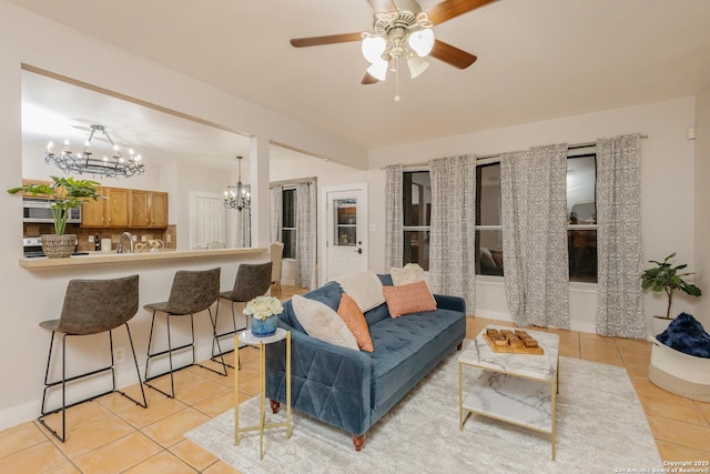 living area with light tile patterned flooring and ceiling fan with notable chandelier