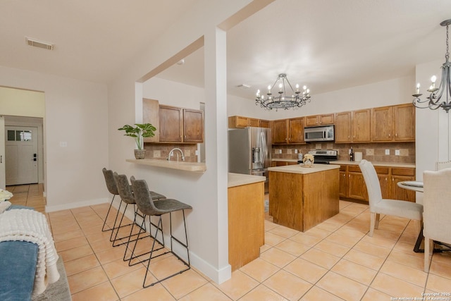 kitchen with light tile patterned floors, visible vents, stainless steel appliances, light countertops, and a chandelier