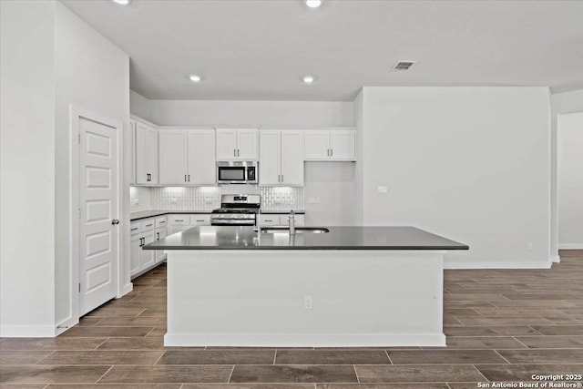 kitchen with appliances with stainless steel finishes, wood finish floors, visible vents, and a sink