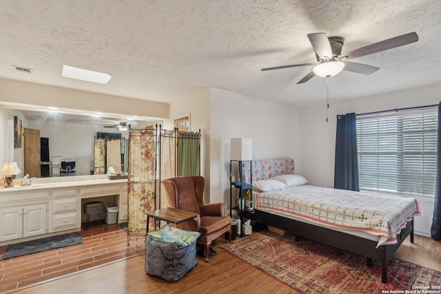 bedroom featuring ceiling fan, a sink, a textured ceiling, and wood finished floors