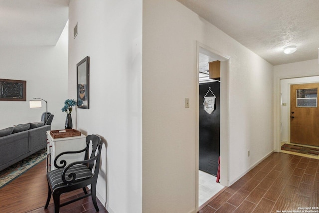 hall featuring wood tiled floor, a textured ceiling, and baseboards