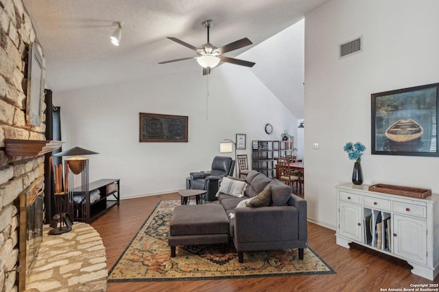 living area with dark wood finished floors, a fireplace, visible vents, ceiling fan, and a textured ceiling