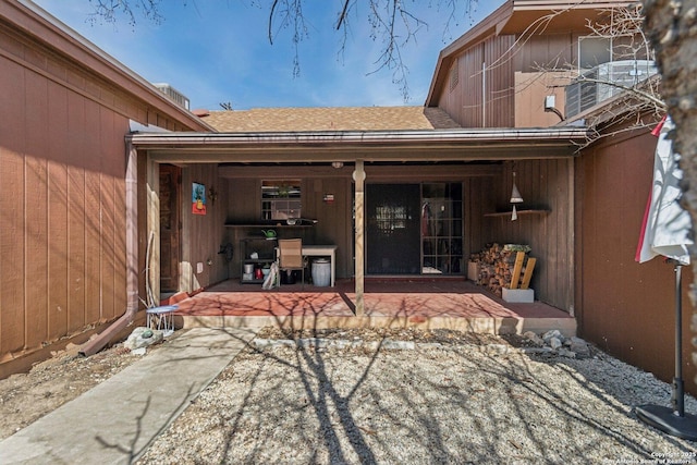 entrance to property featuring a shingled roof