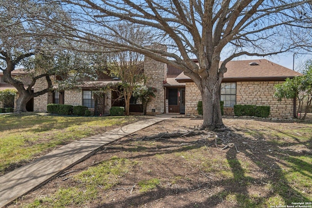 view of front of property featuring stone siding, a shingled roof, and a front lawn