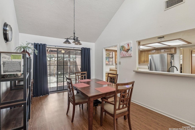 dining space with lofted ceiling, baseboards, visible vents, and wood finished floors