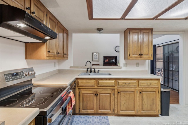 kitchen featuring electric stove, brown cabinets, light countertops, a sink, and under cabinet range hood