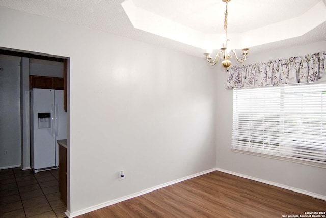 1102 E Hancock, Beeville, TX 78102 - unfurnished room with a chandelier, a raised ceiling, baseboards, and dark wood-type flooring
