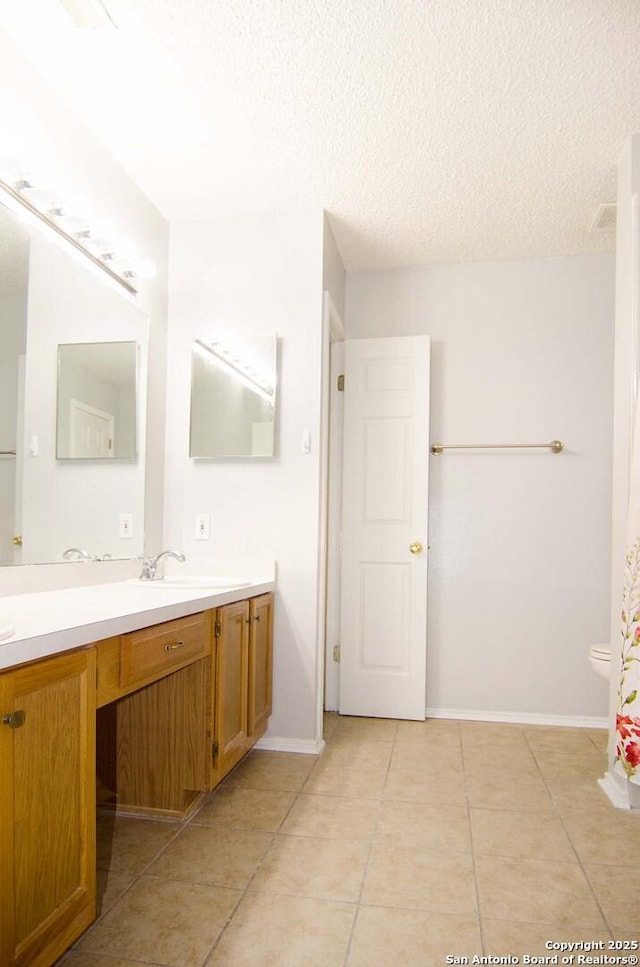 1102 E Hancock, Beeville, TX 78102 - bathroom featuring double vanity, a textured ceiling, tile patterned flooring, toilet, and baseboards