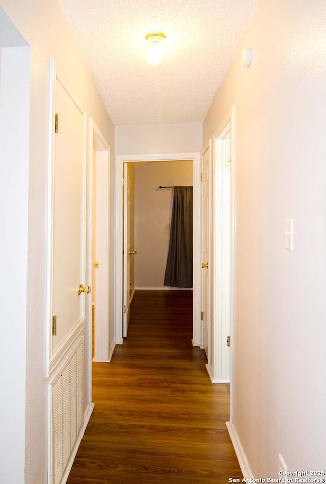 1102 E Hancock, Beeville, TX 78102 - corridor with dark wood-style flooring, baseboards, and a textured ceiling