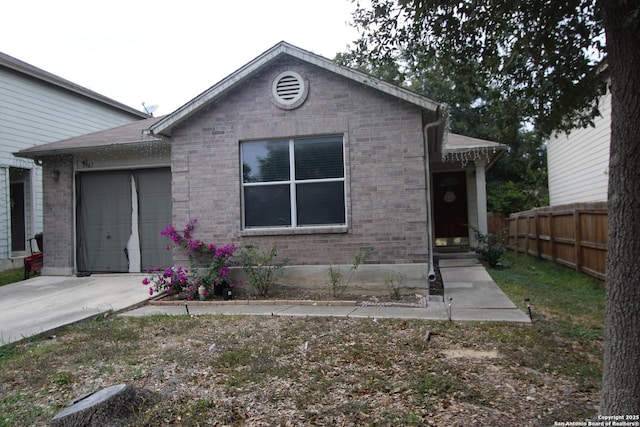 view of front of house with concrete driveway, brick siding, an attached garage, and fence