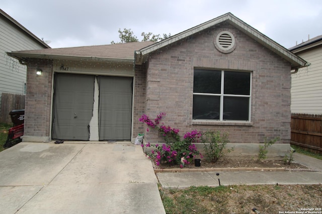 ranch-style home with a garage, brick siding, driveway, and fence