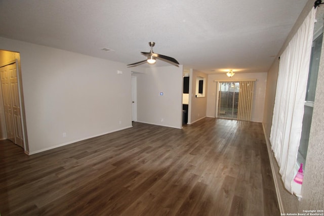 unfurnished living room with baseboards, a textured ceiling, a ceiling fan, and dark wood-type flooring