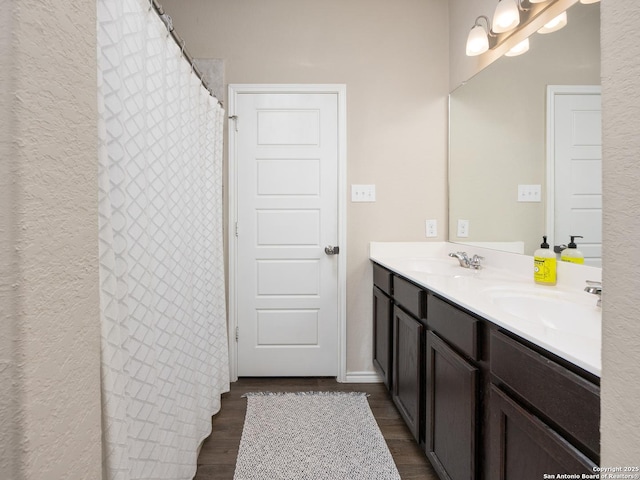 bathroom featuring a chandelier, double vanity, a sink, and wood finished floors