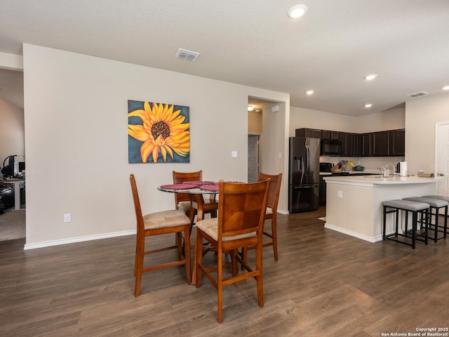 dining room with dark wood-style flooring, visible vents, and baseboards