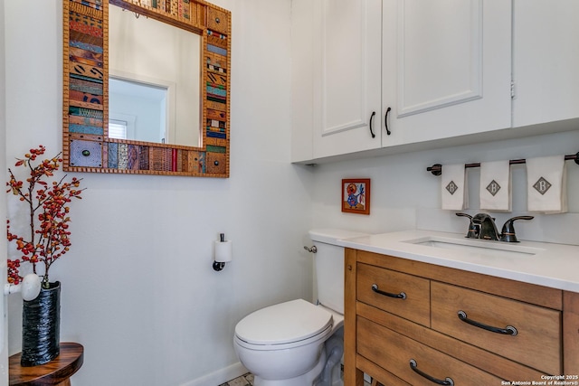 half bath featuring vanity, toilet, and baseboards