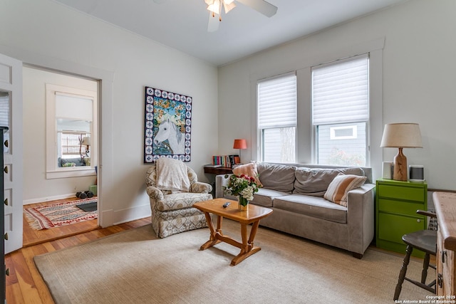 living area featuring plenty of natural light, light wood-style flooring, baseboards, and ceiling fan