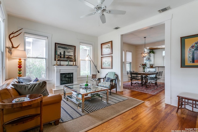 living area with hardwood / wood-style flooring, a glass covered fireplace, and visible vents