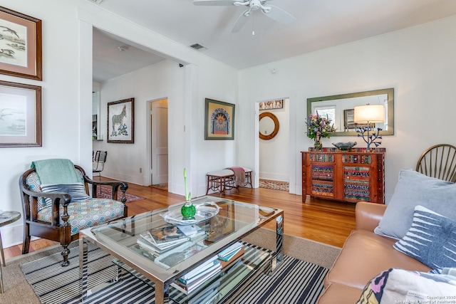 living room featuring baseboards, ceiling fan, visible vents, and wood finished floors