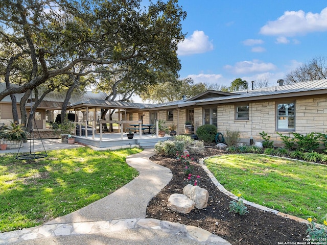 rear view of property featuring stone siding, a lawn, metal roof, and a standing seam roof