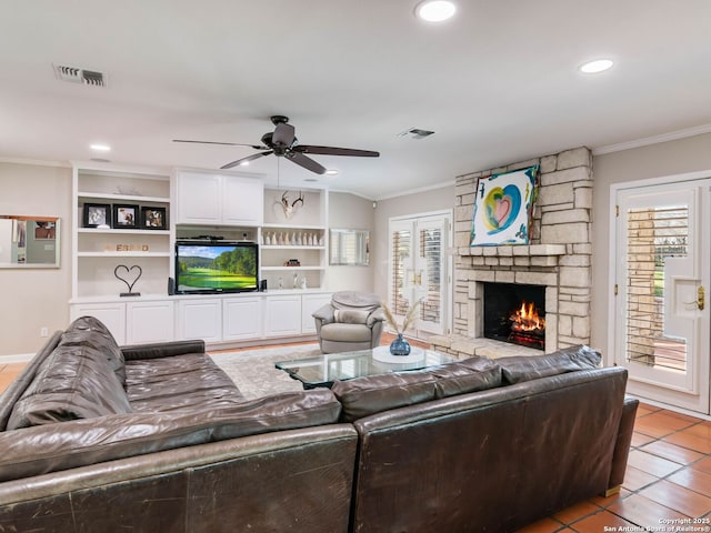 living room featuring a stone fireplace, crown molding, light tile patterned flooring, and visible vents