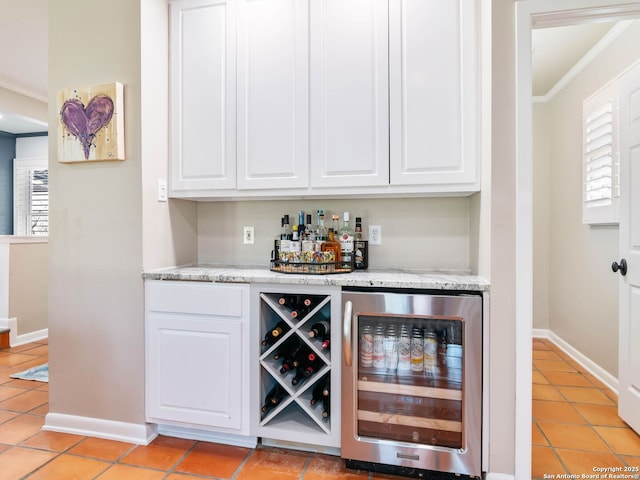 bar featuring wine cooler, a dry bar, crown molding, and baseboards