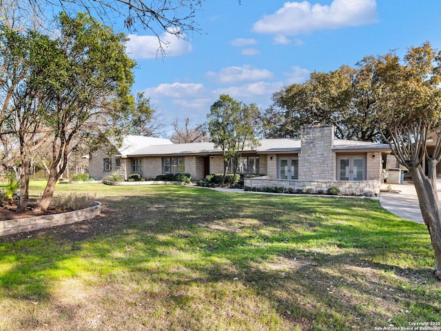 view of front of house featuring stone siding, a chimney, and a front yard